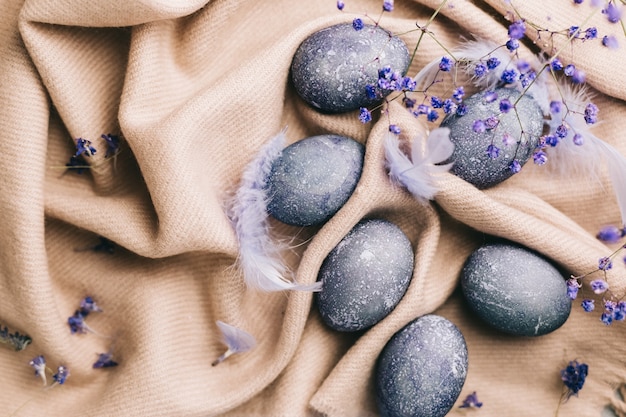 Carte de joyeuses Pâques avec des oeufs bleus, des fleurs, des plumes