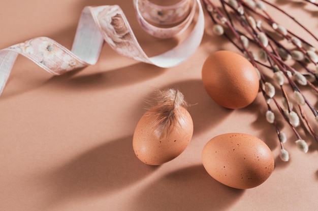 Carte de joyeuses pâques avec des oeufs et des plumes de couleur naturelle