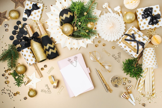 Photo carte de maquette et cahier sur le bureau avec fond de décoration de noël aux couleurs dorées et noires. mise à plat, vue de dessus