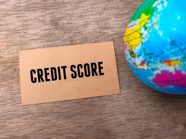 Carte marron et globe terrestre flou avec texte CREDIT SCORE sur fond de bois