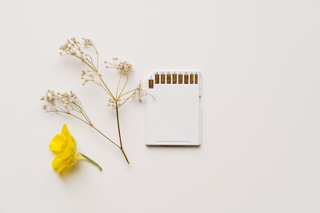 Carte mémoire blanche sur fond blanc avec des fleurs déposées concept de technologie durable respectueux de l'environnement