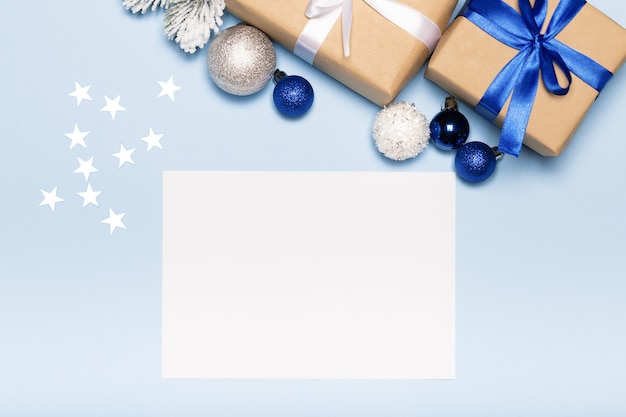 Carte de Noël avec boîte-cadeau en papier et boules sur fond bleu vacances