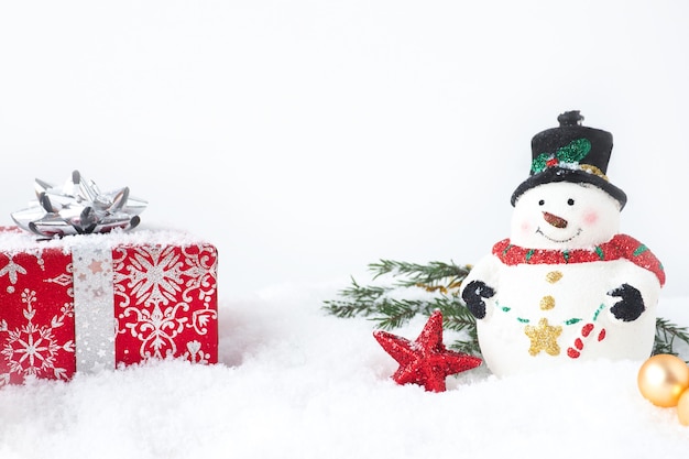 Carte de Noël avec bonhomme de neige, boîte-cadeau rouge, branches de sapin et étoile dans la neige. copie espace.