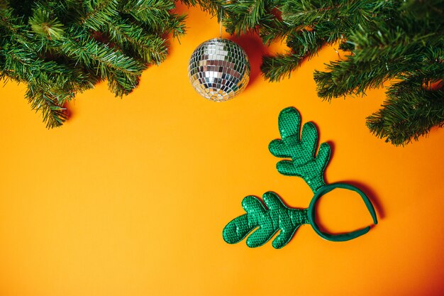 Carte de Noël avec fond. Boule disco en argent et bois de Noël avec des branches de sapin autour de l'orange.