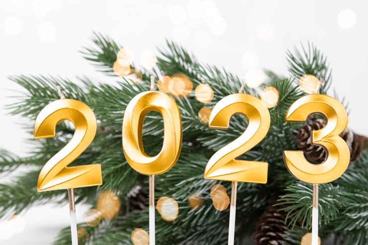 Photo carte de noël avec numéros 2023 en couleur or et lumières de défocalisation branches de sapin vert
