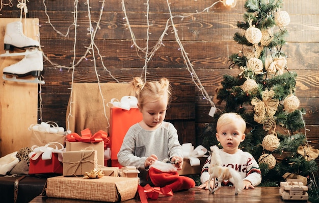 Photo carte de noël pour les enfants d'hiver les petits enfants mignons célèbrent noël le bébé joyeux regarde la caméra à noël à la maison l'ouverture des cadeaux à noël et au nouvel an