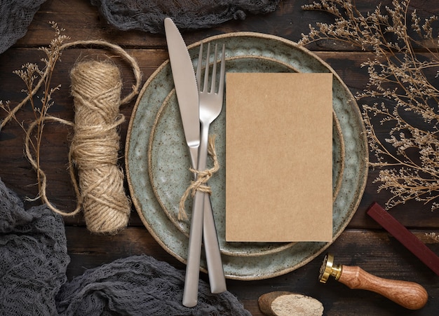 Carte de papier vierge sur plaque avec fourchette et couteau sur table en bois avec décoration bohème autour