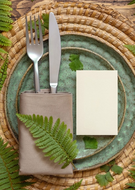 Photo carte de papier vierge sur la table décorée de feuilles de fougère sur la vue de dessus de table en bois. scène de maquette tropicale avec carte de place à plat