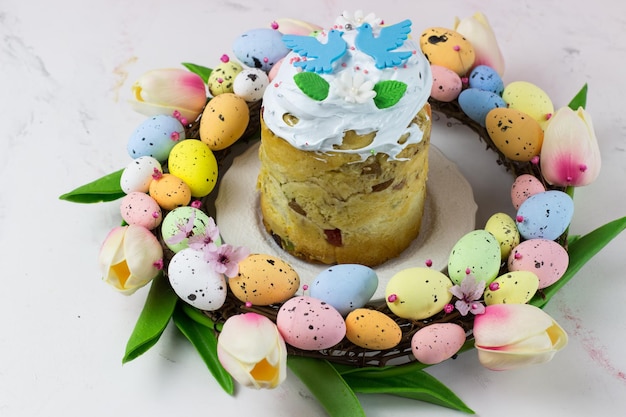 Carte de Pâques Kulich avec fondant au sucre dans une couronne de tulipes et oeufs Fudge à la guimauve avec décoration