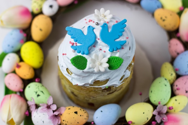 Carte de Pâques Kulich avec fondant au sucre dans une couronne de tulipes et oeufs Fudge à la guimauve avec décoration