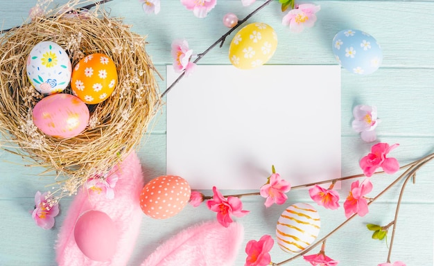 Photo carte de pâques maquette pour le jour de pâques avec des oeufs de pâques et des fleurs de printemps vue de dessus avec espace de copie