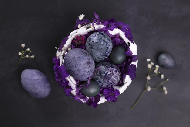 Carte de Pâques avec un panier d'œufs de Pâques violets marbrés. Vue de dessus