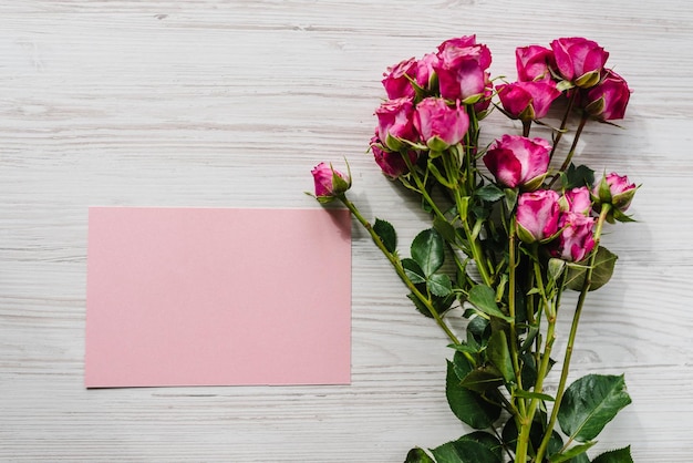 Carte postale avec bouquet de petites roses roses sur fond en bois Message texte de l'espace Carte de voeux de vacances pour la Saint-Valentin Fête des mères des femmes Vue de dessus mise à plat Joyeux anniversaire Invitation de mariage