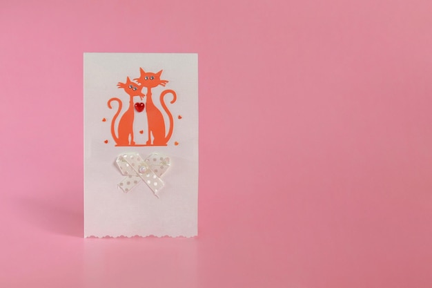 Une carte postale avec des chats amoureux et un coeur sur fond rose le concept de la Saint Valentin Mars
