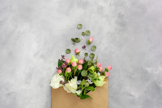 Carte postale avec enveloppe de papier kraft ouverte remplie de fleurs de printemps