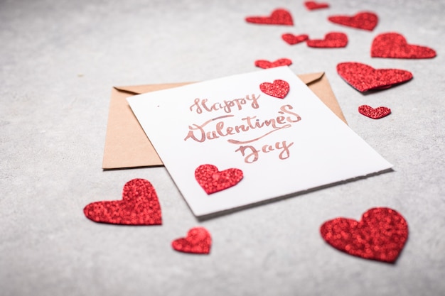 Carte postale de la Saint-Valentin. Inscription de la Saint-Valentin heureuse et coeurs rouges sur un fond gris béton vintage