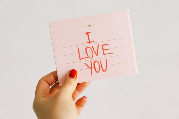 Carte postale de la Saint-Valentin La main d'une femme tient une carte postale avec l'inscription Je t'aime Concept d'amour pour la fête des mères ou la Saint-Valentin Joyeuse Saint-Valentin coeurs Carte de la Saint-Valentin