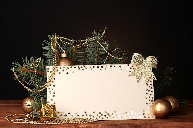 Carte postale vierge, boules de Noël et sapin sur table en bois sur fond marron