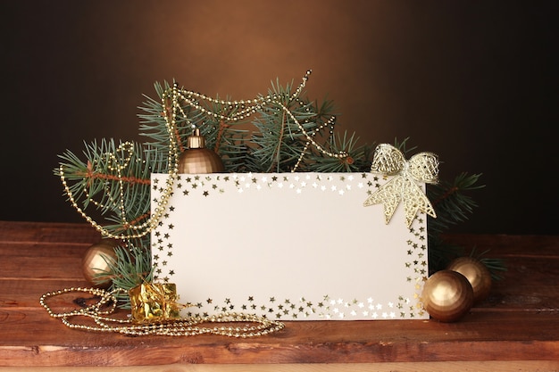 Carte postale vierge, boules de Noël et sapin sur table en bois sur fond marron