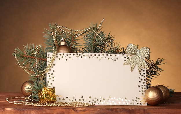 Carte postale vierge, boules de Noël et sapin sur table en bois sur surface brune