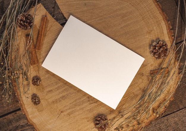 carte postale vierge sur un fond de bois naturel avec des bâtons de cannelle, des cônes de sapin et des branches. Maquiller