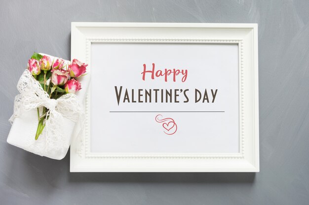 Carte de Saint Valentin. Cadre photo blanc avec cadeau féminin et roses