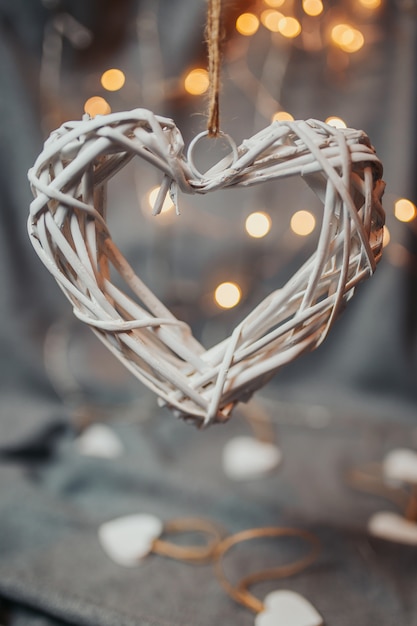 Carte de Saint Valentin. Coeur en osier en bois blanc avec bokeh lumineux. Coeurs avec guirlandes lumineuses.