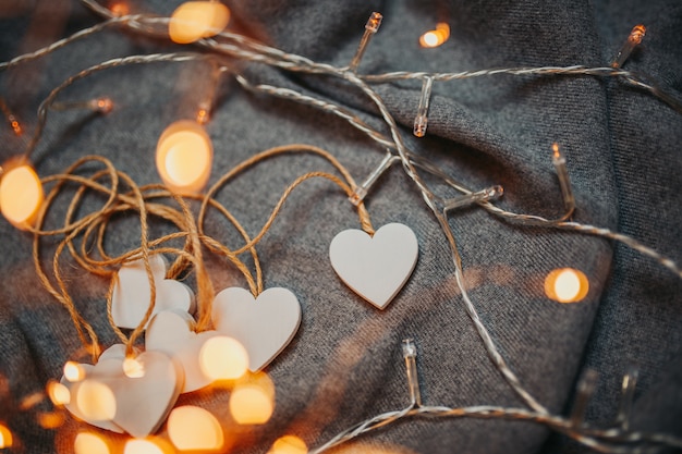 Carte de Saint Valentin. Coeurs en bois blanc sur le gris. Coeurs avec guirlande lumineuse.