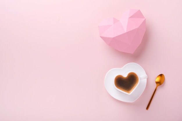 Carte de Saint Valentin. Enveloppe vide rose, biscuit macaron macaron et tasse à café en forme de coeur sur fond rose. 8 mars, Saint Valentin des mères des femmes, anniversaire. Mise à plat, vue de dessus, espace de copie.