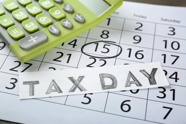 Photo carte avec texte tax day et calculatrice sur le gros plan du calendrier