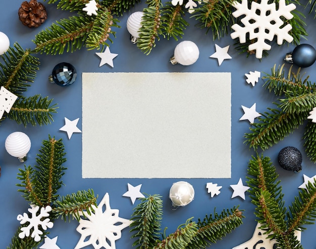 Carte vierge sur fond bleu près de décorations de Noël blanches et de branches de sapin