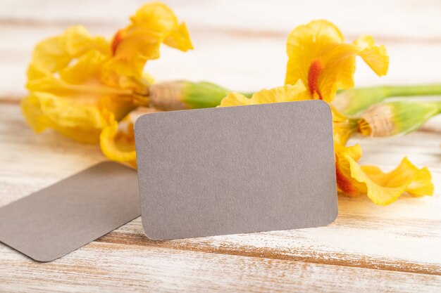 carte de visite grise avec des fleurs jaunes d'iris sur fond de bois blanc. vue latérale, espace de copie