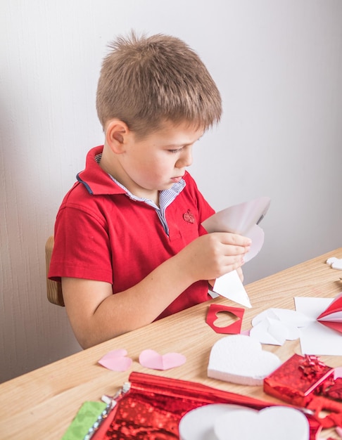 Carte de vœux bricolage avec coeur en papier rouge, symbole de l'amour. Kid boy fait la fête des mères, la Saint-Valentin, carte de voeux. Hobby, concept d'art pour enfants, cadeau de vos propres mains, idées de bricolage pour les enfants