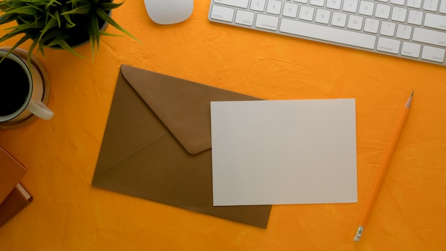 Photo carte de voeux avec enveloppe brune sur table de travail créative avec clavier d'ordinateur et décorations