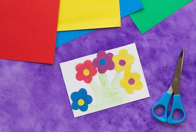 Carte de voeux faite à la main avec des fleurs faites par l'enfant sur le fond violet