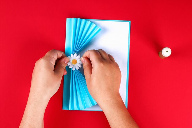 Carte de voeux fête des mères bricolage en forme de rideau avec fleur de camomille en papier sur fond rouge