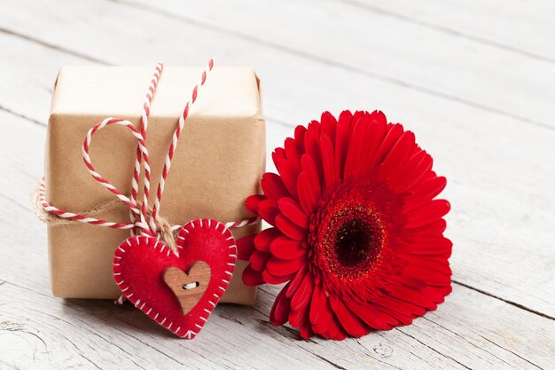 Carte de vœux avec fleur de gerbera et boîte à cadeaux sur fond de bois
