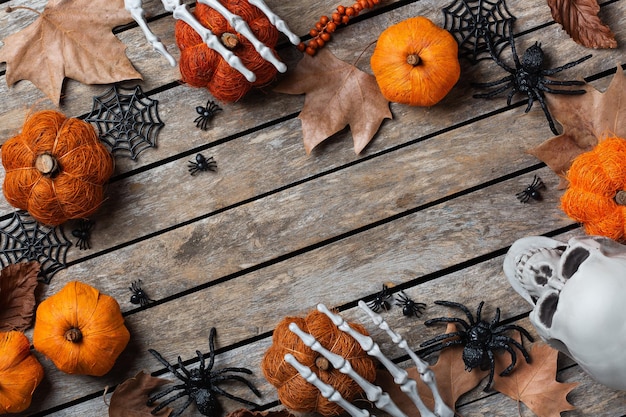 Carte de voeux d'Halloween avec des mains et des feuilles osseuses de crânes de citrouille