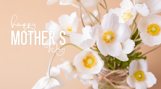 Carte de voeux Happy Mothers Day avec gros plan de fleurs d'anémones blanches sur fond coloré