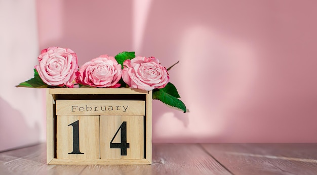 Carte de voeux Happy Valentines Day calendrier en bois et roses roses sur un espace de copie isolé