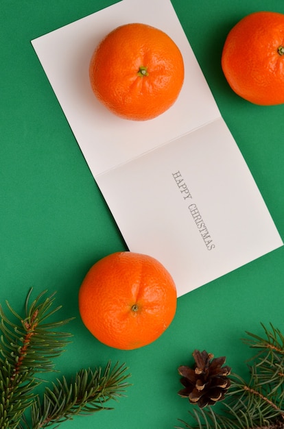 Carte de voeux d'image festive pour noël, mandarines et branches de conifères sur fond vert