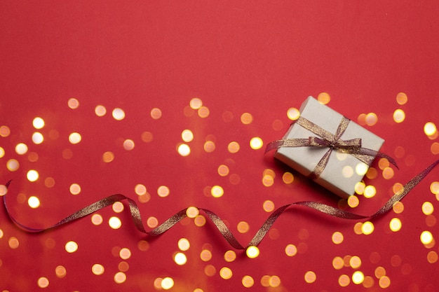 Carte de voeux de joyeuses fêtes avec des confettis scintillants étoiles dorées et une boîte-cadeau sur fond rouge