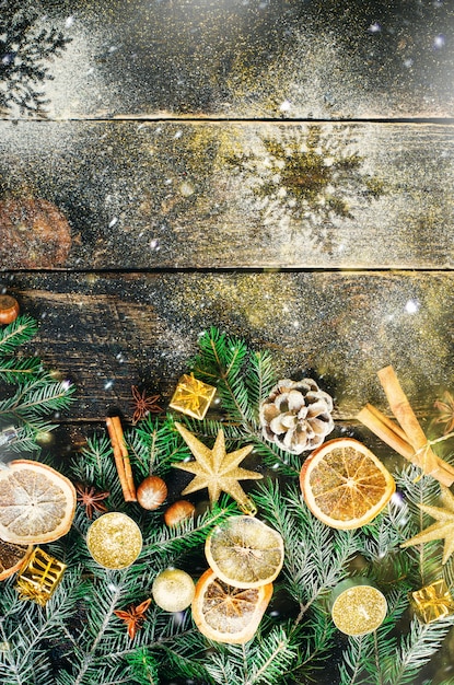 Photo carte de voeux de noël avec des cadeaux, bougies, cônes, bâtons de cannelle, orange sec, arbre vert