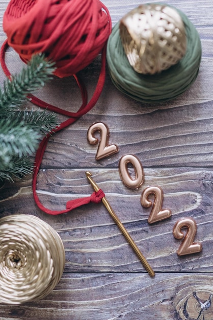 Carte de voeux de Noël et du nouvel an 2022, boules de fil tricoté, crochet et panier tricoté sur une table en bois, vue de dessus