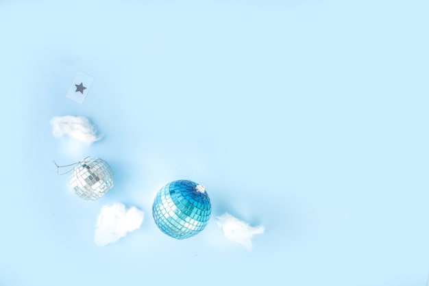 Carte de voeux de Noël simple, invitation à une fête, vente flatlay abstraite avec boules de Noël disco et tableau lumineux, sur fond bleu clair vue de dessus de l'espace de copie