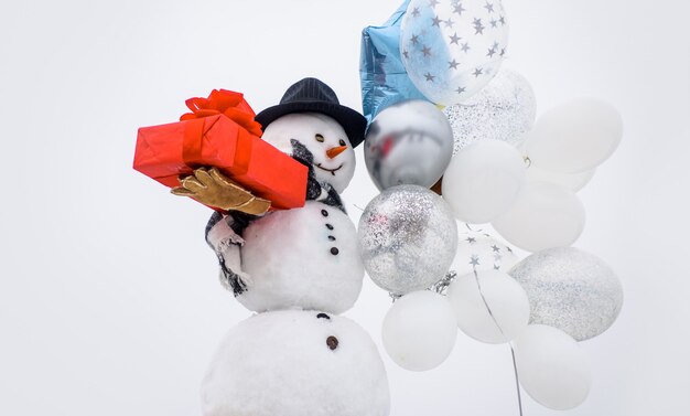 Carte de voeux de nouvel an avec bonhomme de neige bonhomme de neige heureux hiver dans des gants d'écharpe de chapeau avec des ballons à air