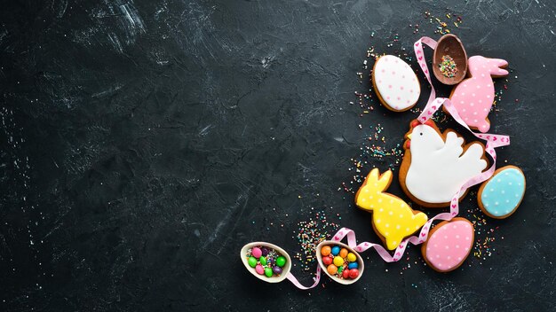 Carte de voeux de Pâques Joyeuses Pâques Biscuits de pain d'épice de Pâques et oeufs colorés décoratifs Sur fond noir Vue de dessus Espace de copie gratuit