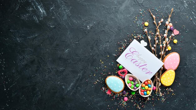 Carte de voeux de Pâques Joyeuses Pâques Biscuits de pain d'épice de Pâques et oeufs colorés décoratifs Sur fond noir Vue de dessus Espace de copie gratuit