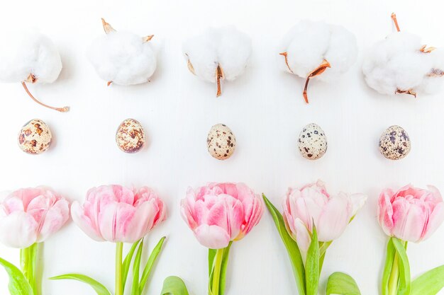 Carte de voeux de printemps. Oeufs de Pâques en coton et rose bouquet de fleurs de tulipes fraîches sur fond de bois blanc rustique