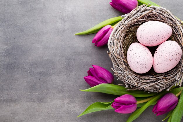 Carte de voeux de printemps. Oeufs de Pâques dans le nid. Tulipes de fleurs de printemps.